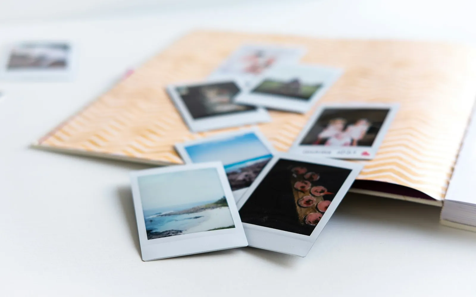 Instant photos spread across an open scrapbook on a white table